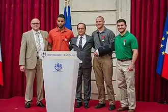 De Franse President François Hollande met de vier mannen die de aanslag verijdeld hebben