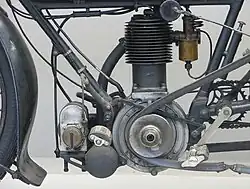 De linkerkant van de motor, met de voorste aandrijfpoelie, de ontstekingsmagneet en daaronder de uitlaatdemper.