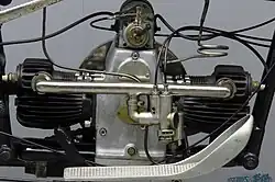 Rechterkant van de motor met de carburateur, de ontstekingsmagneet en het (terugtrap) pedaal voor de achterrem