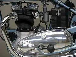 De linkerkant van het eerste motorblok, met achter het deksel voor de primaire transmissie de transmissiedemper (uitstulping), het rempedaal en de accu.