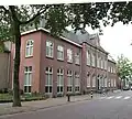 Voormalig kloostergebouw van twee bouwlagen met schilddak, rond 1930 aan de rechterzijde- en in 2000 aan de linkerzijde uitgebreid met een vleugel van twee bouwlagen en een schilddak en aan de achterzijde een kapel uit ca. 1860