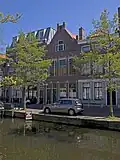 Pand met beneden en bovenwoning rond 1900 gebouwd in een traditionalistische architectuur met invloeden van de Nieuwe Kunst.
