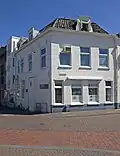 In oorsprong laatgotisch eenlaags woonhuis, in 1902 ingrijpend verbouwd en van een nieuwe voorgevel en bovenverdieping voorzien.