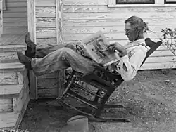 Een Amerikaanse boer in een schommelstoel leest de Progressive Farmer. Foto: G. W. Ackerman, 1931.