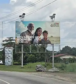 Billboard langs een weg in Suriname ter promotie van het overheidsprogramma "Royalties Voor Iedereen"
