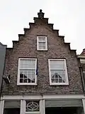 Pand met eenvoudige trapgevel, bekroond door een gebeeldhouwde granaatappel