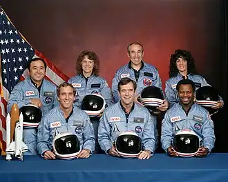 Achterste rij (L-R): Ellison Onizuka, Christa McAuliffe, Gregory Jarvis, Judith Resnik. voorste rij (L-R): Michael J. Smith, Francis "Dick" Scobee, Ronald McNair.