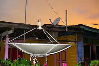 Gezicht op een tweetal schotelantennes in de kampong