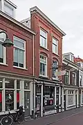 Winkelwoonhuis met voorgevel uit 1902 in traditionalistische vormen met invloeden van de Nieuwe Kunst en een winkelpui uit 1894 in eclectisch-classicistische vormen, beide ontworpen door C.J.L. Kerbergen. Het is van belang vanwege de zorgvuldig gedetailleerde architectonische behandeling en als werk in het oeuvre van C.J.L. Kerbergen.