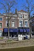 Winkelwoonhuis, in de tweede helft van de 19de eeuw gebouwd in een sobere traditioneel-classicistische bouwtrant. Onderpui uit 1923 in traditionalistisch-classicistische vormen.
