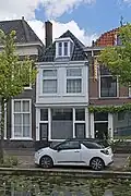 Winkelwoonhuis, in oorsprong wellicht een 17e-eeuws woonhuis. Voorgevel in de 19e eeuw gemoderniseerd in traditioneel-classicistische vormen. Winkelpui uit circa 1905.