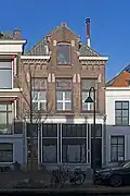 Winkelwoonhuis, in 1903 als melkinrichting met bovenwoning gebouwd in een verzorgde traditionalistische bouwtrant, naar ontwerp van C.J.L. Kersbergen, ten behoeve van de R.K. Delftsche Coöperatieve Vereeniging ¿Ons doel¿ die achter het pand een zuivelfabriek had die bereikbaar was vanaf de Houthaak.