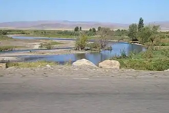 De Čùj vanuit Kirgizië (omgeving Tokmok) met aan de overkant Kazachstan (heuvels)