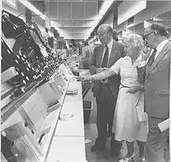 Burgemeester Harm Buiter en zijn vrouw brengen een bezoek aan het nieuwe EKP in Groningen. Directeur Meijering (rechts) legt de werking van de Japanse stempelmachine uit (1979)