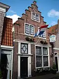 Huis met trapgevel. In latere pui een gesneden deur en eenvoudig snijraam, elk geflankeerd door verdiepte pilasters