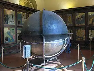 Zaal met geografische kaarten aan de wanden en grote wereldbol in het midden