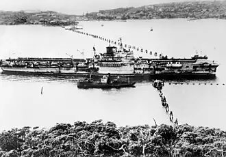 Het Britse vliegdekschip HMS Formidable passeert langs het anti-duikbotennet van de haven van Sydney in 1945. De zwarte schoorsteen was het gevolg van een kamikazeaanval waarbij een Japans vliegtuig neerstortte op het vliegdek.
