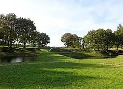 Zicht op de dam en aarde wallen van het redoute