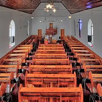 Binnenzijde van de kerk. Boven de preekstoel staat geschreven: ‘God is Liefde’