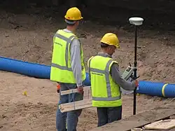 Landmeters met piketten, ze zetten met behulp van GPS de houten paaltjes uit voor het markeren van de plek van een nieuw te bouwen object.