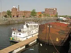 kleurenfoto van kanaal met boot en textielfabriek