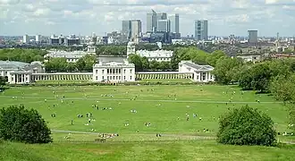 Het lagere deel van Greenwich Park gezien vanaf de top van de heuvel met in de verte Queen's House, de twee torens van Greenwich Hospital en op de achtergrond Canary Wharf.