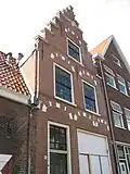 Pand met trapgevel, gedodekopt, met bogen en natuurstenen blokken boven de vensters versierd, haarlems type