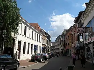 Gezicht op de straat vanaf het minderbroedersklooster met de Ludovicuszaal van het klooster links op de voorgrond
