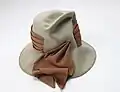 Een hoed met meerlagige hoedband die in de kroon verdwijnt, weer naar buiten komt en eindigt in losse linten die gestrikt kunnen worden