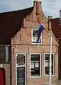 Huis met in- en uitgezwenkte gevel met door pilasters afgesloten vlechtingenfries en gemetseld jaartal 1592