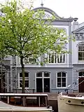 Pand met gepleisterde lijstgevel met stucversieringen. Segmentvormig fronton