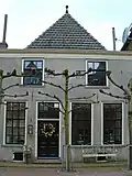 Huis met eenvoudige gepleisterde gevel met rechte kroonlijst, twee gevelstenen met eenhoorns in rolwerk-cartouches, steen met engelenkopje en sierankers (Huis met de eenhoorn)