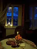 Een huiskamer met mandarijnen, kaars, kerstkoekjes en andere kerstversiering