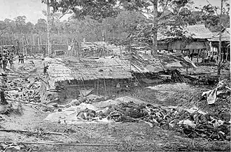 Kuil bezaaid met lijken in Kuta Reh na de verovering door Van Daalen op 14 juni 1904. Links enkele Nederlandse soldaten.