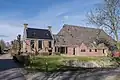 Kop-hals-rompboerderij met onderkelderd voorhuis met zesruitsvensters tussen topgevels waarboven schoorstenen met borden