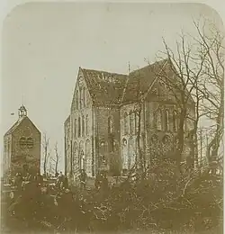 Mannen kappen en zagen hout voor de zwaar vervallen kruiskerk na de storm van 17 december 1869