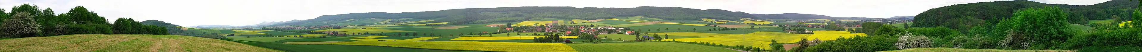 uitzicht vanaf het zuidwesten op de kam van de Ith. Blick von Südwesten auf den Höhenzug des Ith; Vanaf Oelkassen in de richting Dielmissen (links), Lüerdissen (midden) en Scharfoldendorf bij Eschershausen (rechts); op de achtergrond delen van de bergrug Hils