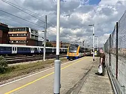 De overground rijdt binnen, aan de andere kant van de langeafstandssporen een class 345 van TfL Rail op weg naar Shenfield.