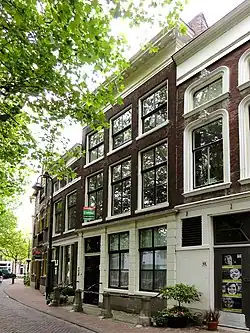 Pand met lijstgevel. Deur met levensboom in het bovenlicht, schuiframen en stoeppalen met stangen