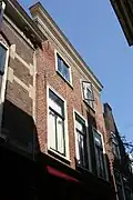 Pand met gerestaureerde rijzige bakstenen gevel, met rechte kroonlijst. Ondergevel gewijzigd