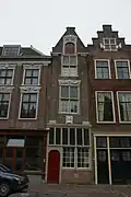 Pand met smalle puntgevel met beeldhouwwerk en oorspronkelijke kruisvensters. Aan weerszijden pilasters