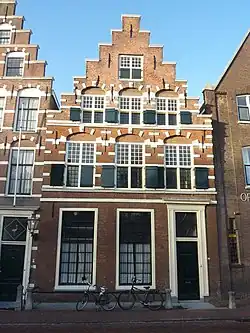 Pand met trapgevel met zandstenen lijsten, banden en blokken, vensterbogen. Hardstenen stoep en palen. Gevel in Haarlemse trant. Boventop vernieuwd en vereenvoudigd 19e eeuw