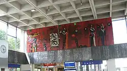 Noordwand van de stationshal met de wandschildering tussen fries en plafond.