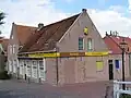 Pand met lage gevel, kleine roeden, zadeldak in topgevels eindigend
