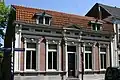 Woonhuis, gebouwd in het laatste kwart van de negentiende eeuw, in Eclectische stijl. Het hoekhuis heeft de voorgevel aan de Markt, de zijgevel grenst aan de Omgang.