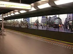 Kunstfoto's op de wanden van het metrostation. Hier wordt het Muntplein in Brussel afgebeeld.