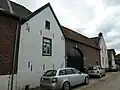 Hoeve met binnenplaats, grotendeels van baksteen en met puntgevel van mergel; op poort sluitsteen
