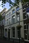 Twee huizen achter een gepleisterde lijstgevel met Lod.XIV-consoles onder de kroonlijst en stucversieringen. Inwendig een Lod.XV-plafond