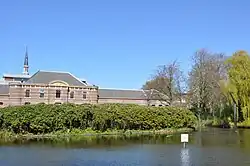 Zicht vanuit de paleistuin over een vijver en de Koninklijke Stallen