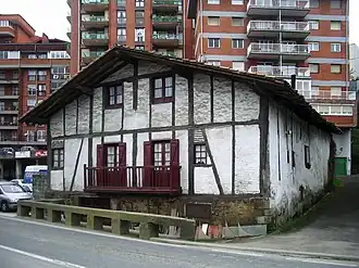 Een historische boerderij met daarachter woontorens in Loiola